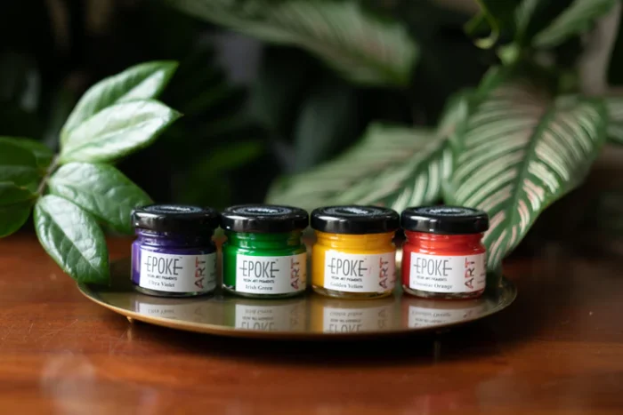 Close-up of Happy Vibe Mini Pigment Kit Set for Resin Art in bright shades of Cinnabar Orange, Golden Yellow, Irish Green, and Ultra Violet, in 25g and 20g jars.
